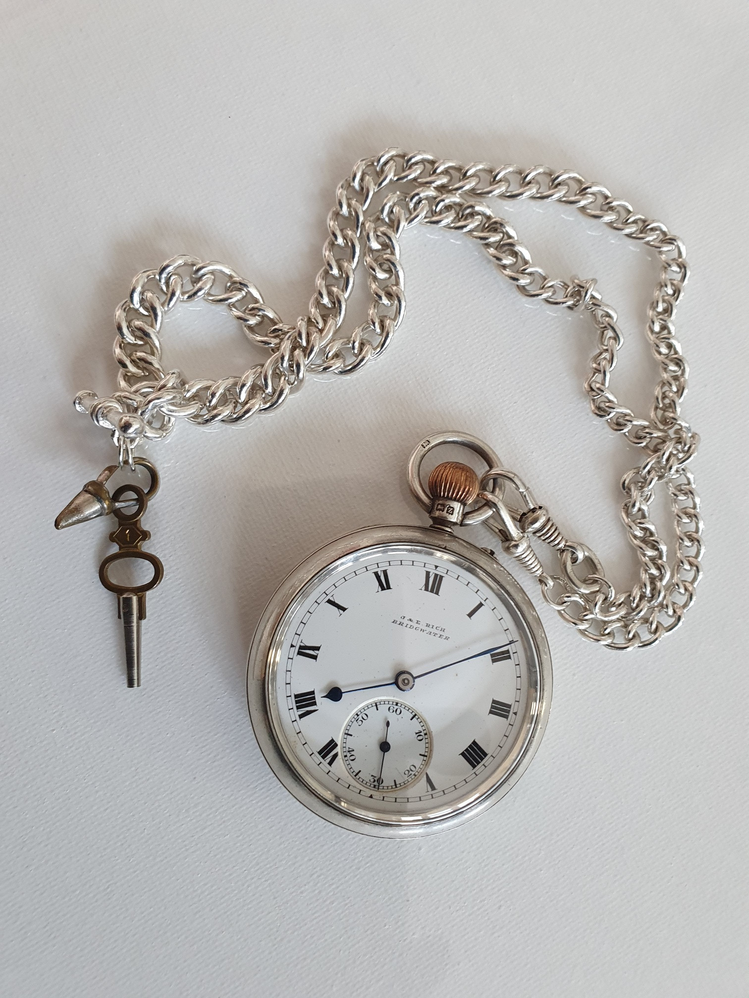 J&E Rich silver pocket watch with chain and key.